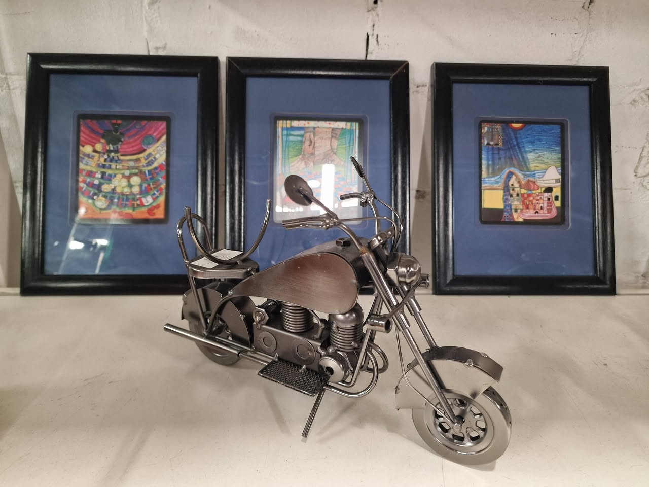 Dekoratives Motorradmodell und gerahmte Kunst im Recyclingkaufhaus
